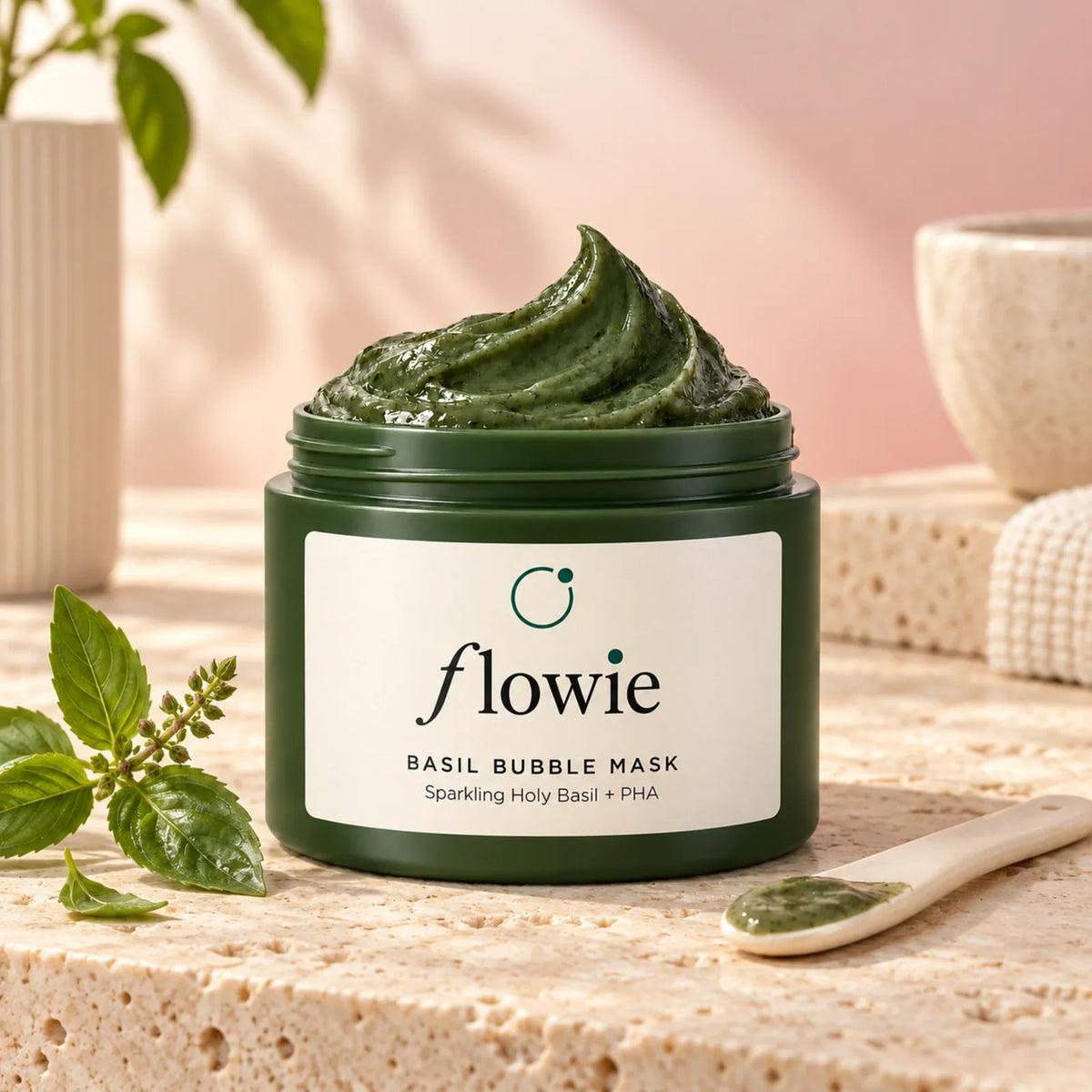 Open dark green Basil Bubble Mask jar with green mask and a cream ceramic spatula on pale stone
